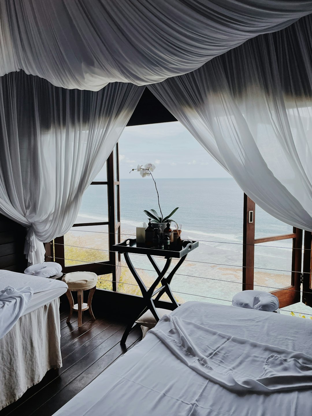 Two massage beds face a window overlooking the ocean.