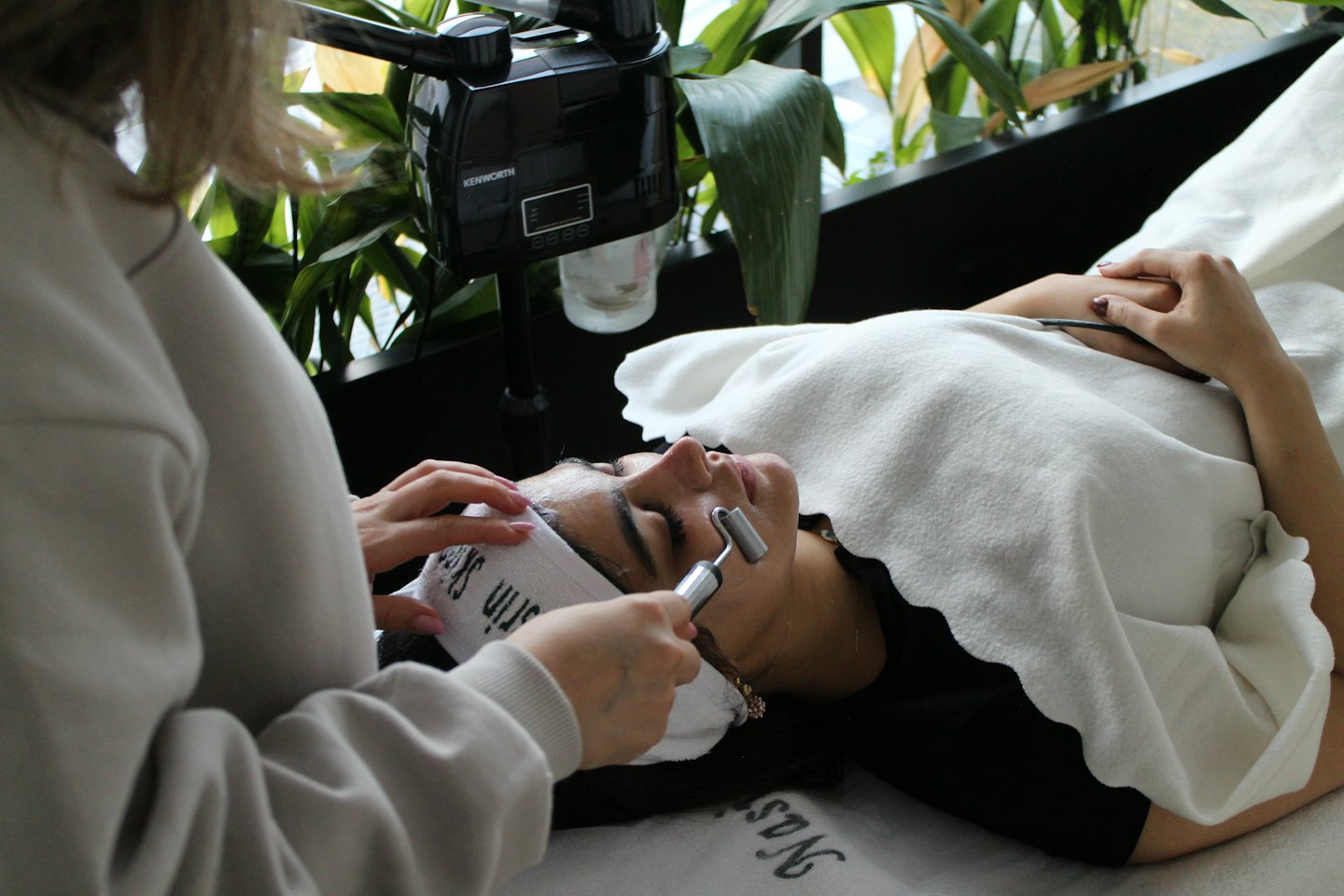 Therapist rolling client's forehead with spa tool.