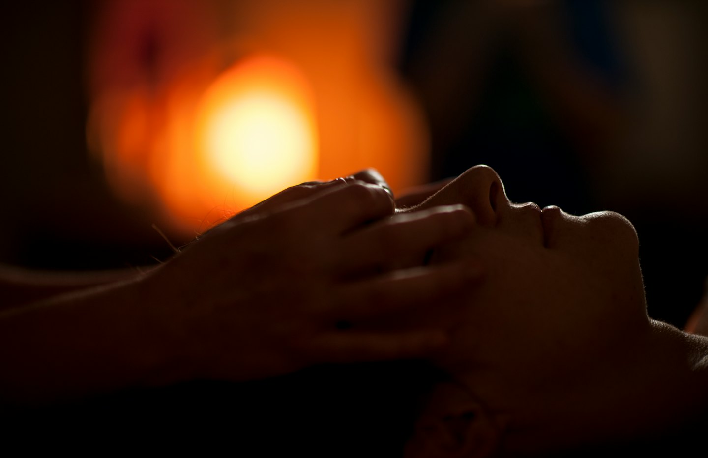 Person receiving a relaxing facial massage in a dimly lit spa.